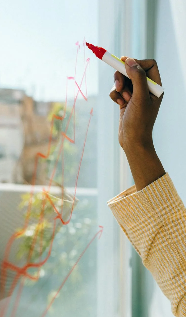 drawing financial projections on a glass whiteboard.